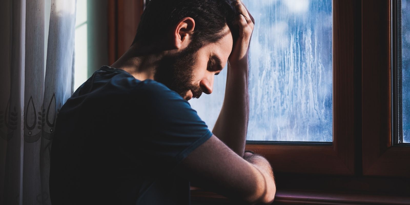 Man gazes through window alone